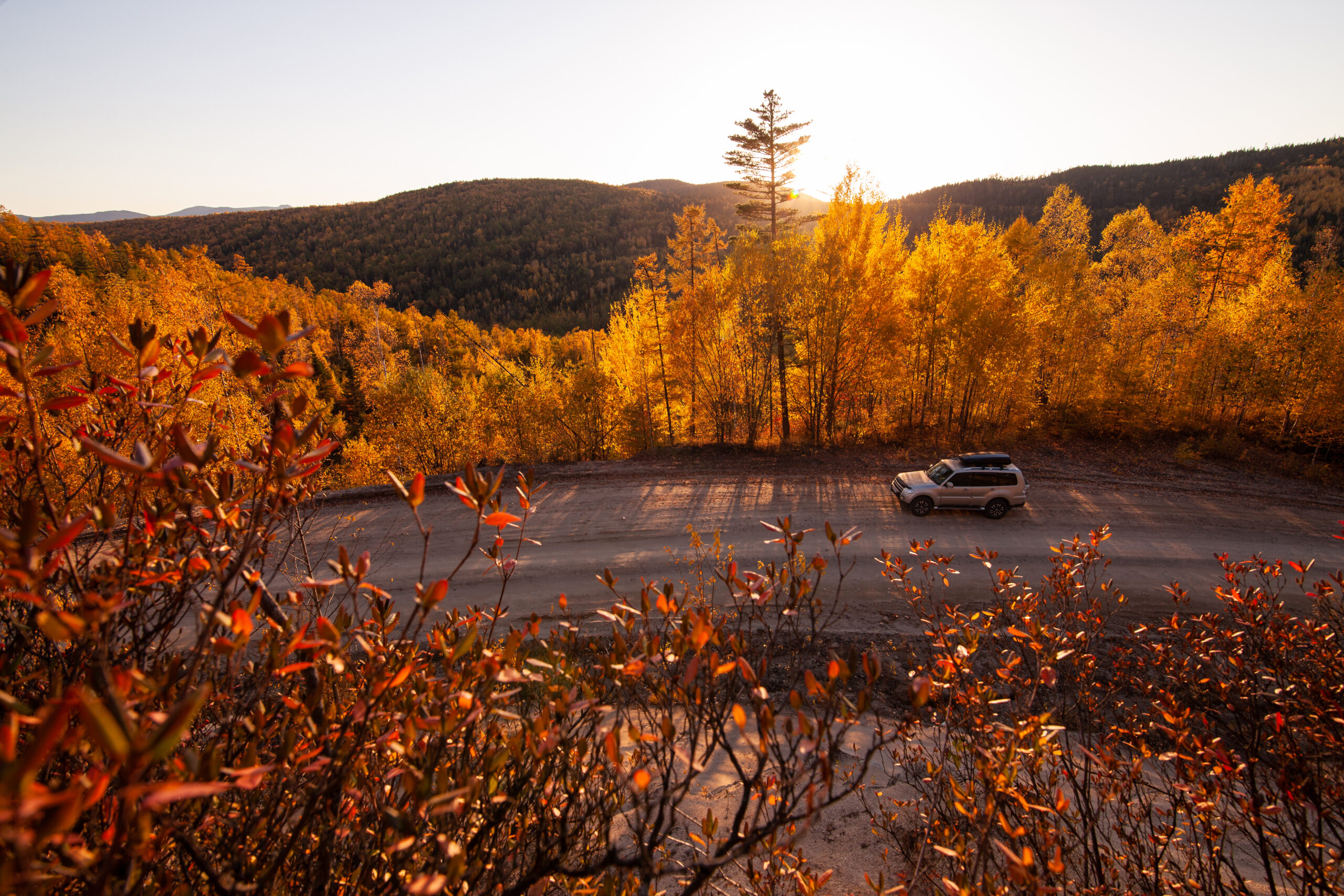 Mitsubishi Pajero on scenic autumn road in taiga